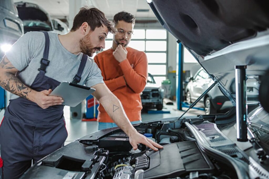 Two men are inspecting the cars engine in Surrey, BC